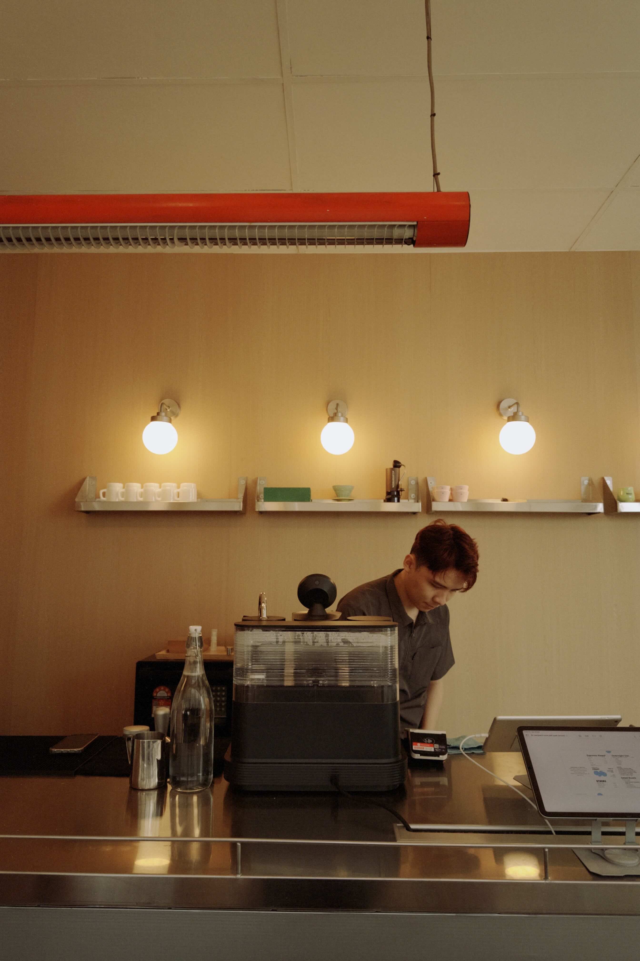 Person working at a counter with shelves and lights in the background