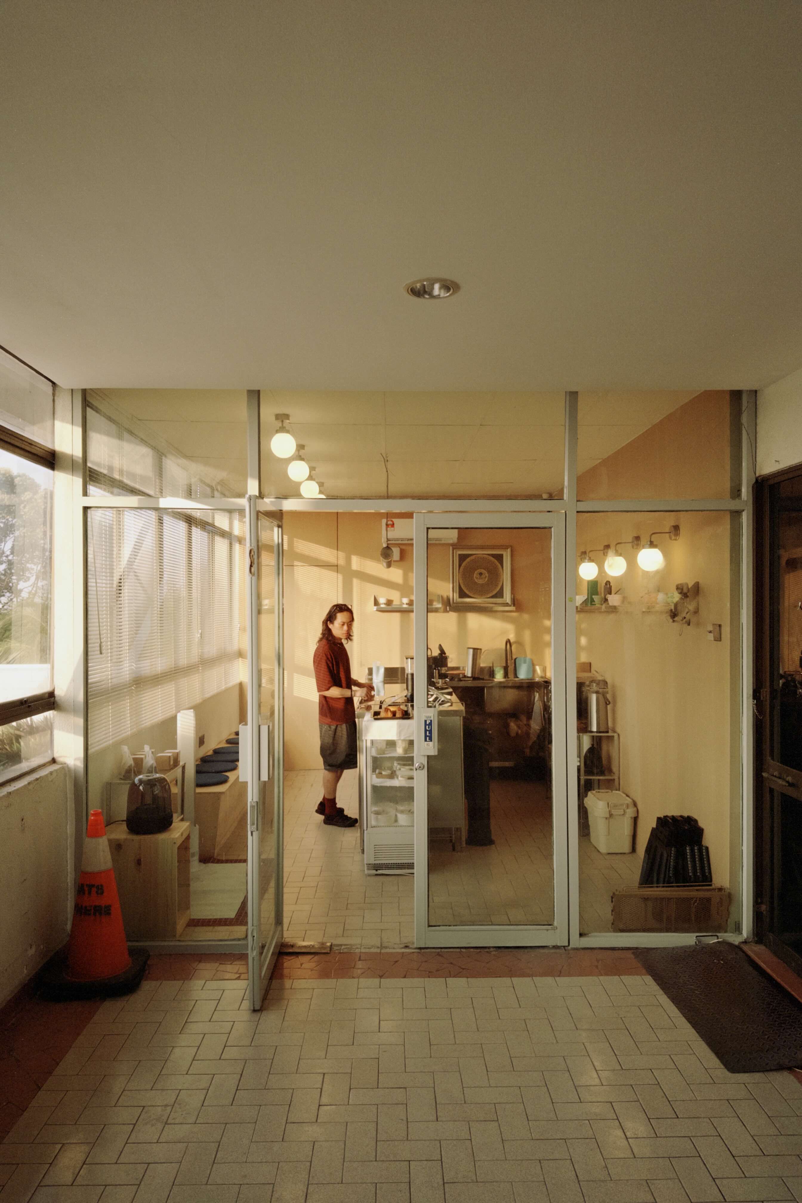 Person standing in a kitchen with glass doors leading to an outdoor area.