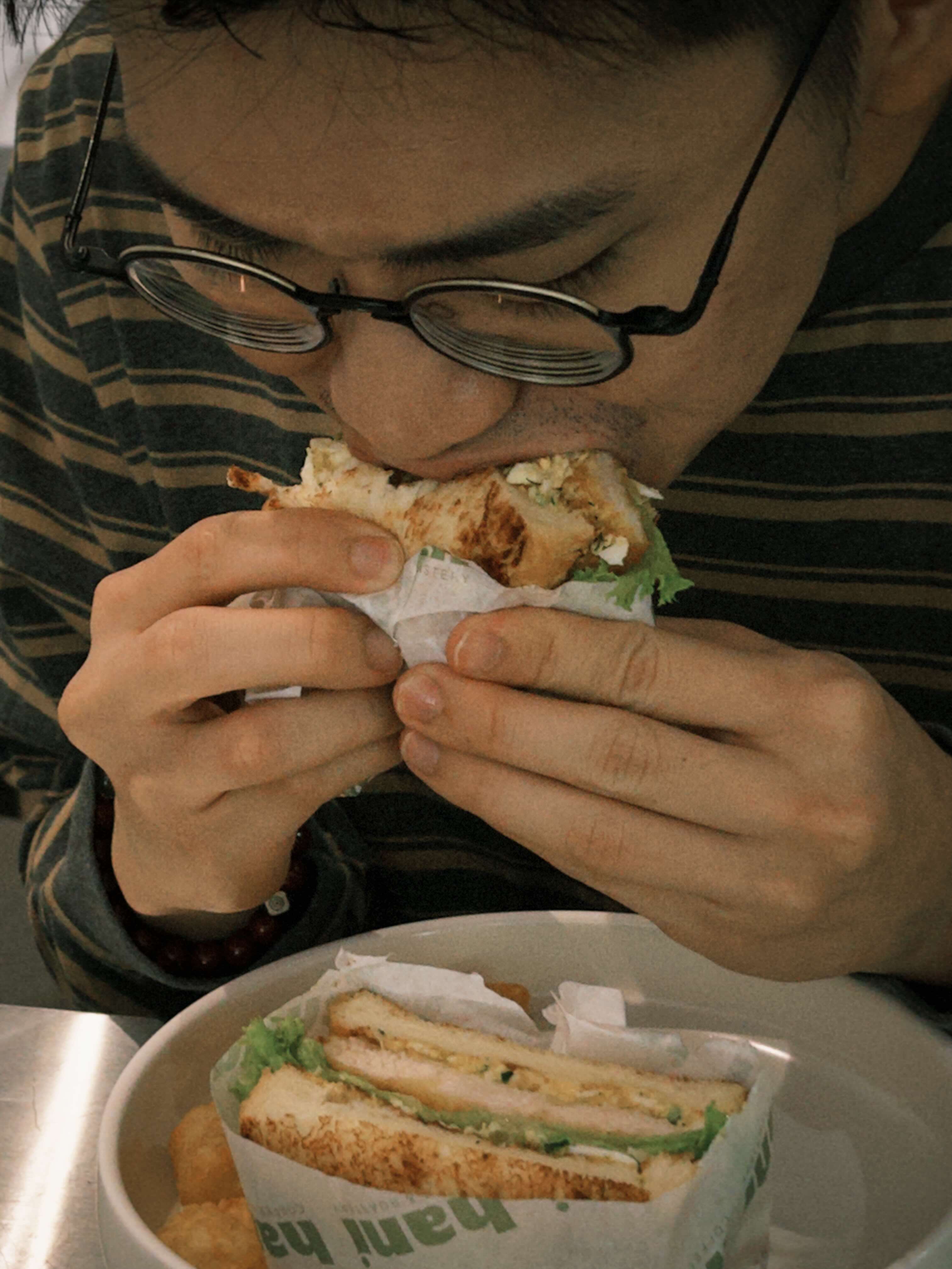 Person eating a sandwich with a focus on the food and hands